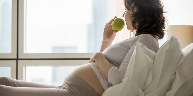 Photo of pregnant woman eating apple